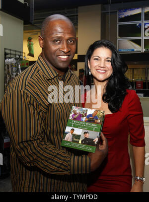 Elisa Gaudet stands with former New York Giants player Perry Williams as she signs copies of her new book 'Two Good Rounds', 19th Hole Stories from the World's Greatest Golfers, at the book launch party at Golfsmith in New York City on December 6, 2011.       UPI/John Angelillo Stock Photo