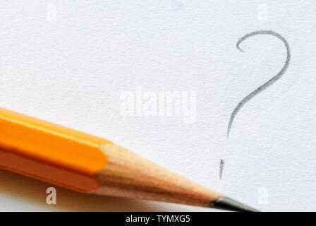 Sharp pencil lying next to question mark on white paper with copy space. Stock Photo