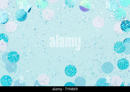 Festive frame of iridescent confetti and sparkles on pastel blue background. Stock Photo
