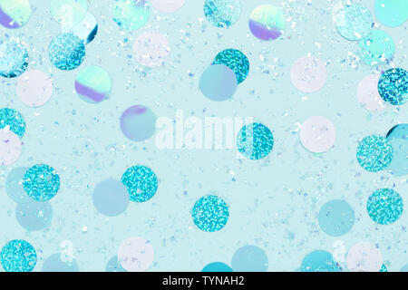 Carnival decorations Festive iridescent confetti and sparkles on pastel blue background . Stock Photo