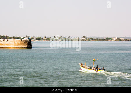 Diu, Daman, Gujarat, India - Circa 2019: boat approaching the stone wall of a castle in the sea in diu gujarat india. The blue sea, the brightly decor Stock Photo