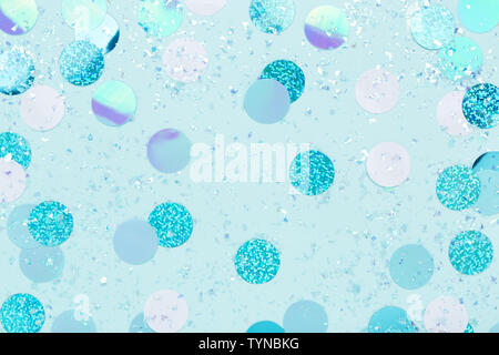 Carnival decorations Festive iridescent confetti and sparkles on pastel blue background . Stock Photo