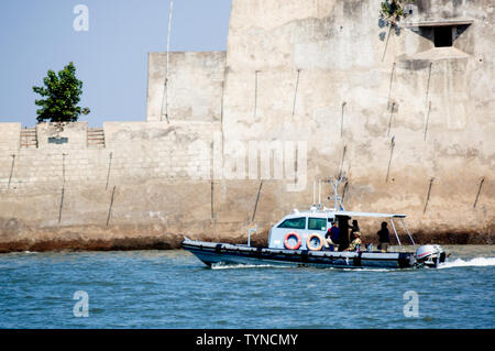 Diu, Daman, Gujarat, India - Circa 2019: boat approaching the stone wall of a castle in the sea in diu gujarat india. The blue sea, the brightly decor Stock Photo