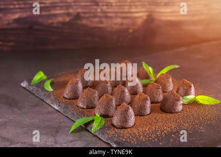 Homemade chocolate truffles with mint sprinkled with cocoa powder on slate. Focus on truffles Stock Photo