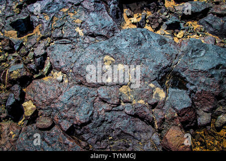 Black volcanic stones on the sandy beach. It is rock texture. Stock Photo