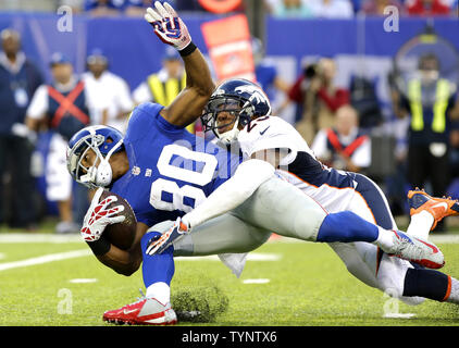 New York Giants Victor Cruz is tackled by Denver Broncos Chris Harris after a 10 yard gain in the third quarter in week 2 of the NFL season at MetLife Stadium in East Rutherford, New Jersey on September 15, 2013. The Broncos defeated the Giants 41-23.    UPI /John Angelillo Stock Photo