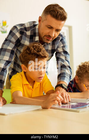 Helpful teacher. Smart bearded man helping his student while conducting a lesson Stock Photo