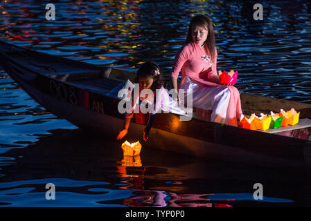 Vietnamese mother and daughter dropping lanterns into the river in Hoi An Vietnam during the Hoi An Full Moon Lantern Festival Stock Photo