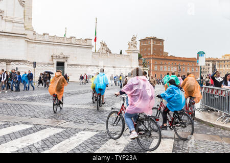 ROME, ITALY - APRIL 22, 2019: Tourists on bicycles on a rainy day near the Altar of the Fatherland. Stock Photo