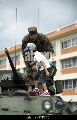 Sgt. Daniel Vreeland helps a child climb on top of a light armored vehicle Nov. 20 during the Japan Ground Self-Defense Force Festival on Camp Naha, Okinawa, Japan. The festival celebrated the 6th anniversary of the 15th Brigade and the 44th anniversary of Camp Naha. Daniel, a Santa Clarita, California, native, is an LAV crewman with Combat Assault Battalion, 1st Marine Division, III Marine Expeditionary Force. Stock Photo