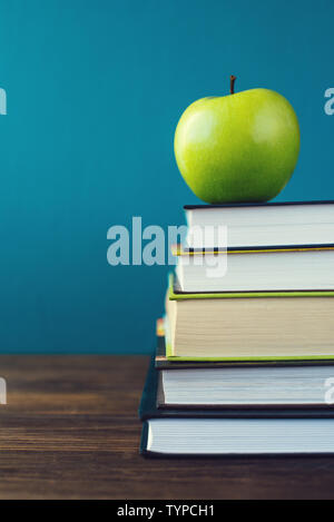 School books with apple on desk over school board background Stock Photo