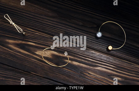 Modern Golden bracelets on wooden background Stock Photo