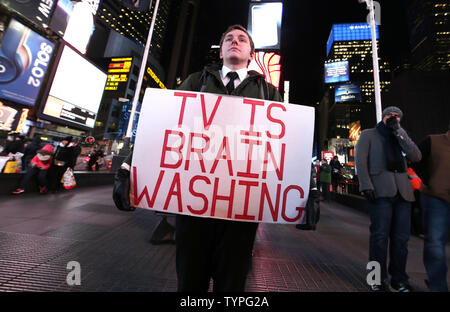 A man holds a sign bellow a giant new billboard that hangs below the Marriott Marquis when it is illuminated for the first time in Times Square in New York City on November 18, 2014. The new screen stands eight stories tall and is nearly as long as a football field, spanning the entire block from 45th Street to 46th Street on Broadway. Nearly 24 million LED pixels, each containing tiny red, blue and green lights, make up the display, giving it higher resolution than even the best of today's top-of-the-line television sets.    UPI/John Angelillo Stock Photo