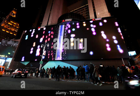 People look up at a giant new billboard that hangs below the Marriott Marquis when it is illuminated for the first time in Times Square in New York City on November 18, 2014. The new screen stands eight stories tall and is nearly as long as a football field, spanning the entire block from 45th Street to 46th Street on Broadway. Nearly 24 million LED pixels, each containing tiny red, blue and green lights, make up the display, giving it higher resolution than even the best of today's top-of-the-line television sets.    UPI/John Angelillo Stock Photo