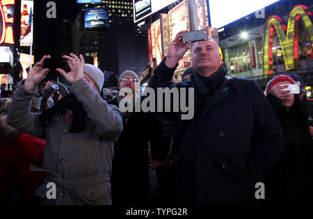 People look up at a giant new billboard that hangs below the Marriott Marquis when it is illuminated for the first time in Times Square in New York City on November 18, 2014. The new screen stands eight stories tall and is nearly as long as a football field, spanning the entire block from 45th Street to 46th Street on Broadway. Nearly 24 million LED pixels, each containing tiny red, blue and green lights, make up the display, giving it higher resolution than even the best of today's top-of-the-line television sets.    UPI/John Angelillo Stock Photo