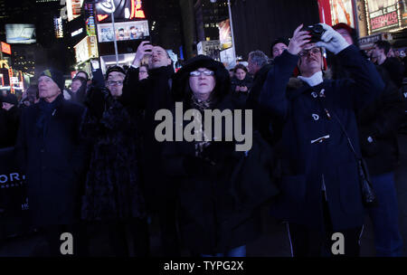 People look up at a giant new billboard that hangs below the Marriott Marquis when it is illuminated for the first time in Times Square in New York City on November 18, 2014. The new screen stands eight stories tall and is nearly as long as a football field, spanning the entire block from 45th Street to 46th Street on Broadway. Nearly 24 million LED pixels, each containing tiny red, blue and green lights, make up the display, giving it higher resolution than even the best of today's top-of-the-line television sets.    UPI/John Angelillo Stock Photo