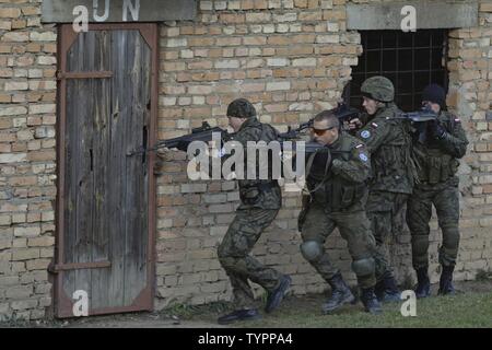 Pfc. Mariusz Kwidzinskei (middle), and soldiers assigned to the Polish 6th Airborne Battalion, 16th Airborne Brigade, prepare to breach the door to an abandoned building during a bi-lateral training event with Paratroopers, 3rd Platoon, Company D, 2nd Battalion, 503rd Infantry Regiment, 173rd Airborne Brigade, in an urban operations training facility in Wedrzyn, Poland, Nov. 21, 2016. A part of the 173rd Abn. Bde.’s mission in East Europe is to strengthen the NATO Alliance by augmenting its light infantry tactical capabilities with shared tactics by focusing on relationships, techniques and pr Stock Photo
