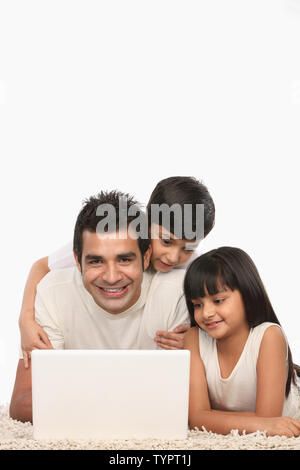 Indian man working on a laptop with his children Stock Photo