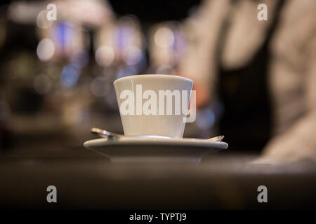 white espresso cup with a spoon on a table  in an Italian bar with a blurry and sparkling background Stock Photo