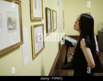 A woman stops to look at part of the exhibition where the original 'Alice in Wonderland' manuscript is on display at the press preview one day before a public exhibition titled 'Alice: 150 Years of Wonderland' celebrating the 150th anniversary of the publication of Lewis Carrol's 'Alice's Adventures in Wonderland' begins at The Morgan Library & Museum in New York City on June 25, 2015. The display features the original manuscript of the book  on loan from the British Library in London as well as  original correspondence, unique drawings, hand colored proofs, rare editions, vintage photographs Stock Photo