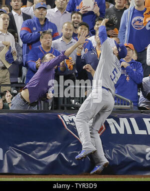 A fan, right, reaches into the playing field with his glove as Philadelphia  Phillies first baseman Ryan Howard slides trying to catch the foul ball hit  by Atlanta Braves Alex Gonzales during