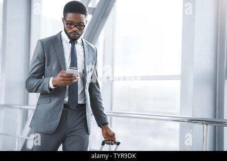 Businessman Texting on Smartphone Walking in Airport Terminal Stock Photo