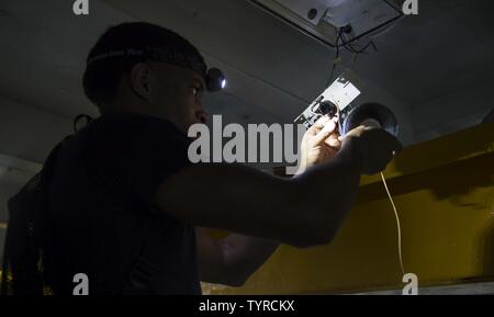 GULF (Nov. 22, 2016) Seaman Daniel Lewis, from Chicago, converts a fluorescent lighting fixture to L.E.D in the forecastle of the aircraft carrier USS Dwight D. Eisenhower (CVN 69) (Ike) as part of the ship's energy conservation effort as the flagship of the Great Green Fleet. Lewis works as an electrician's mate aboard Ike. Ike and its Carrier Strike Group are deployed in support of Operation Inherent Resolve, maritime security operations and theater security cooperation efforts in the U.S. 5th Fleet area of operations. Stock Photo