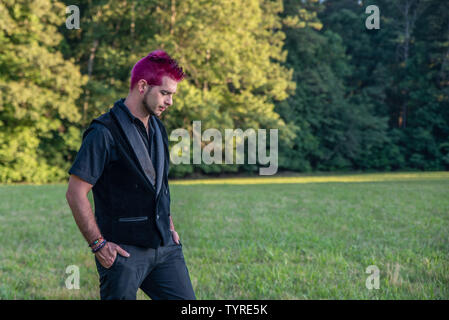 Diverse alternative looking white male caucasian with spkiy pink hair staring down at the ground. Feeling depressed, sad, or defeated. Pierced brow. Stock Photo