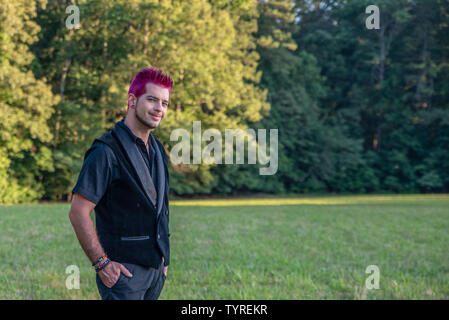 White caucasian male man smiling at camera. Diverse alternative look with pink hair and empty room space for copyspace or text. Grinning, knowing, fri Stock Photo