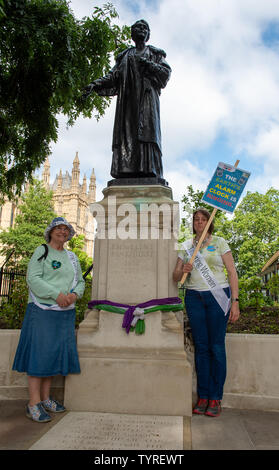 Victoria Tower Gardens, Westminster, London, UK. 26th June, 2019. WI members Jan and Helen from Gloucestershire pose under the statue of suffragette Emmeline Pankhurst following the Time is Now lobby. This was a mass lobby for climate, nature and people held around the streets in Westminster. Credit: Maureen McLean/Alamy Stock Photo