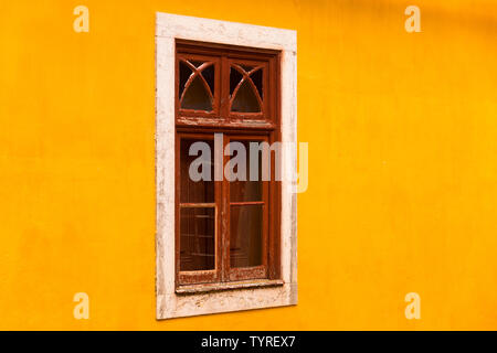Wood framed window with white stone surround on brightly coloured yellow wall at UNESCO World Heritage site of the National Palace of Sintra, Portugal Stock Photo