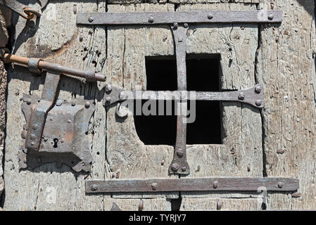 Old medieval wooden door with window and wrought iron fittings Stock Photo
