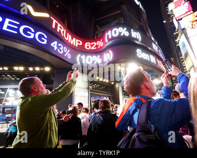 People take photos as crowds gather below a news scroll as they watch the election returns being broadcasted on giant video screens in Times Square on Election Day on November 8, 2016 in New York City. Democratic nominee Hillary Clinton and Republican candidate Donald J. Trump are battling to become the 45th US president following contentious campaigns.     Photo by Monika Graff/UPI Stock Photo