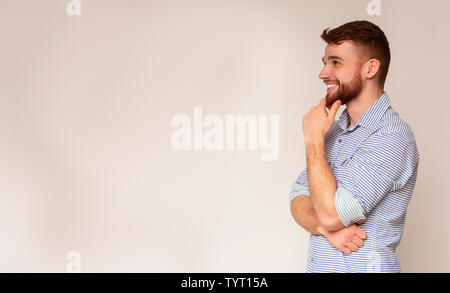 Young smiling man thinking and looking away on free space Stock Photo