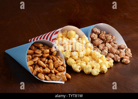 honey peanuts with caramel popcorn and honey sesame seed almonds in paper cones Stock Photo