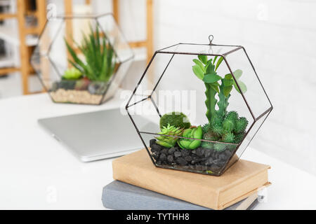 Laotop, vase with plants and books stack on table Stock Photo