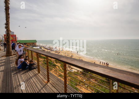 Tel Aviv, Israel - April 13, 2019: Beautiful view of a crowded beach in a modern city during a cloudy and sunny day. Stock Photo