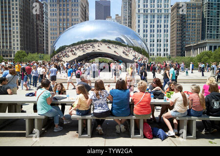 people having lunch in millennium park on a  busy saturday morning in summer near the cloud gate bean sculpture in Chicago IL USA Stock Photo