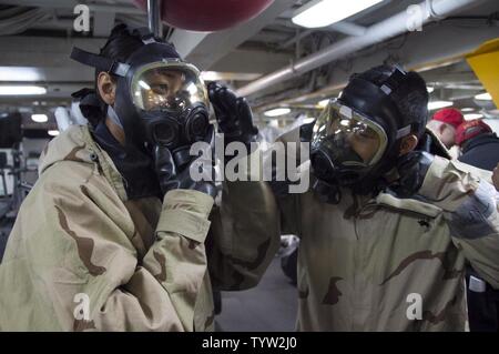 SASEBO, Japan (Nov. 30, 2016) Petty Officer 3rd Class Laniece Watters (left), from Columbus, Ohio, and Petty Officer 2nd Class David Sacdal, from San Francisco, Calif., don MCU-2P gas masks during a chemical, biological, radiological drill aboard amphibious assault ship USS Bonhomme Richard (LHD 6). Bonhomme Richard, forward-deployed to Sasebo, Japan, is serving forward to provide a rapid-response capability in the event of a regional contingency or natural disaster. Stock Photo