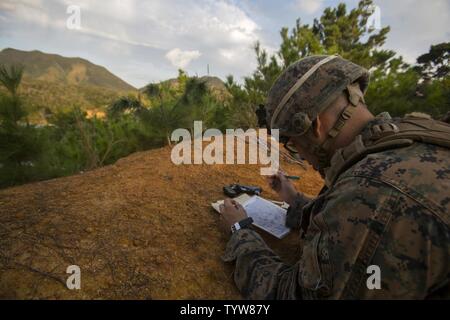 A U.S. Marine with Kilo Company, 3d Battalion, 3d Marine Regiment with the unit deployment program, sketch their surroundings during a division squad competition at Landing Zone Cardinal, Camp Schwab, Okinawa, Japan, Nov. 30, 2016. Marines participate in the annual competition to test their endurance, occupational intelligence and cohesion. Stock Photo