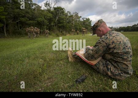 U.S. Marine Corps Cpl. Pilkington observes marines participating in a division squad competition at Landing Zone Cardinal, Camp Schwab, Okinawa, Japan, Nov. 30, 2016. Marines participate in the annual competition to test their endurance, occupational intelligence and cohesion. Stock Photo