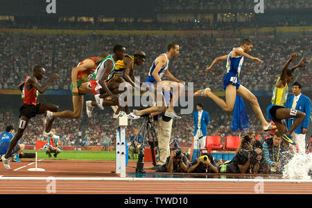 Runners fly over a hurdle, landing in a water hazard, during the opening lap of the Olympic men's 3000m steeplechase final in Beijing August 18, 2008. Kenya's Brimin Kiprop Kipruto won the gold medal in a time of 8:10.34, France's Mahiedine Mekhiss took the silver and the bronze went to Richard Kipkemboi Mateelong of Kenya.   (UPI Photo/Stephen Shaver) Stock Photo