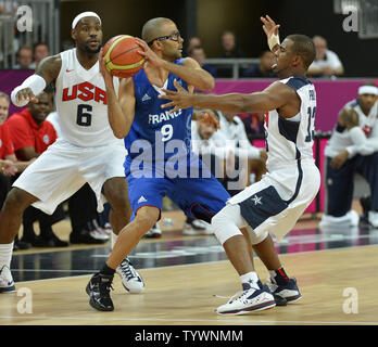 France's Tony Parker (C), who also plays for the NBA's San Antonio Spurs, is defended by United States' Chris Paul (R), who also plays for the Los Angeles Clippers and LeBron James, who also plays for the Miami Heat, during the United States-France Men's Basketball Preliminary competition at the 2012 Summer Olympics, July 29, 2012, in London, England.              UPI/Mike Theiler Stock Photo