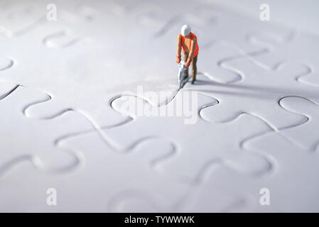 Miniature person constructing puzzles, making way for the team and working concept. Effort concept Stock Photo