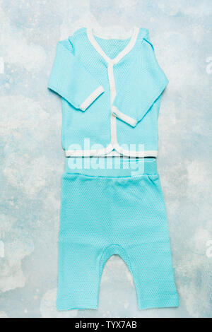 Fashionable cotton textile summer suit for newborn baby on blue textured background. Flat lay style. Vertical shot Stock Photo