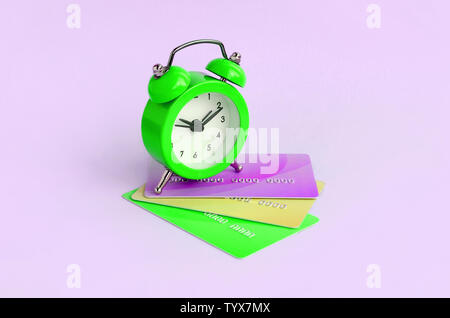 Small green alarm clock lies on colored credit cards. The concept of modern fast online banking and funds transfer operations Stock Photo