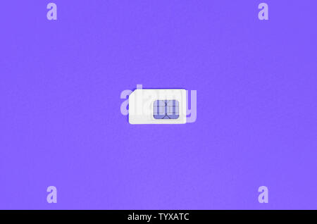 Subscriber identity module. New white SIM card on bright violet color background. Minimal flat lay top view Stock Photo