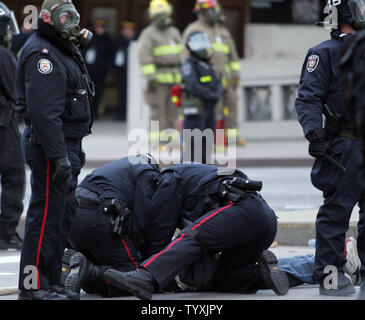 Ottawa police subdue an anti-Bush protester outside the conference centre on Rideau Street as President George W. Bush meets inside with opposition Conservative party leader Stephen Harper on November 30, 2004.  Three levels of police -- local, provincial (OPP), and national (RCMP) were out in full force to secure the presidential visit routes and venues.  (UPI Photo/Grace Chiu) Stock Photo