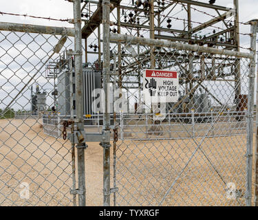 High voltage warning sign showing danger of electrocution surrounding an electrical substation supplying electricity Stock Photo