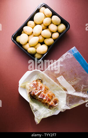 Raw roastbeef meat  prepared, caparisoned with pig caul fat and rosemary inside a sous vide bag ready to be cooked with a rooner with small potatoes, Stock Photo